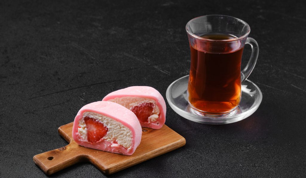mochi strawberry with a glass of tea beside it